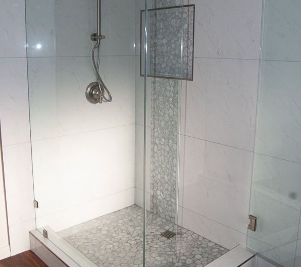 Tiled walk-in shower with glass panels and a chrome showerhead.