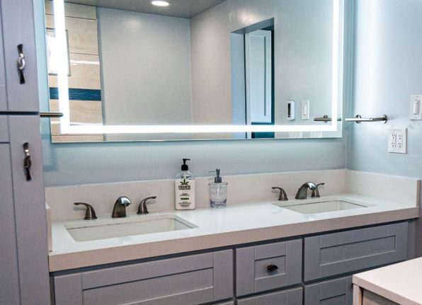 Modern bathroom vanity with double sinks, large mirror, and light gray cabinetry