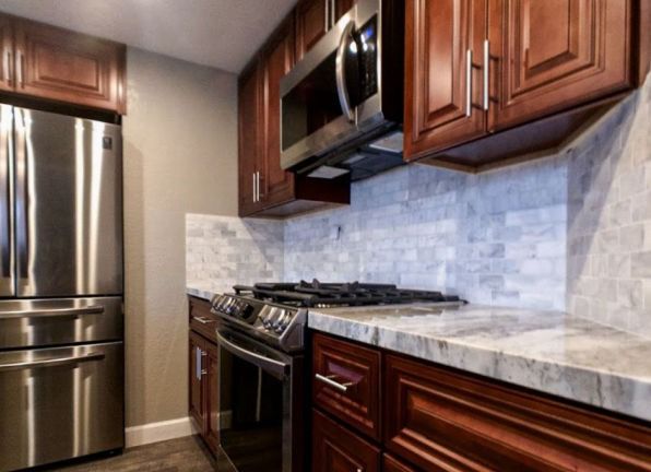 Modern kitchen with stainless steel appliances, dark wood cabinets, and light tile backsplash
