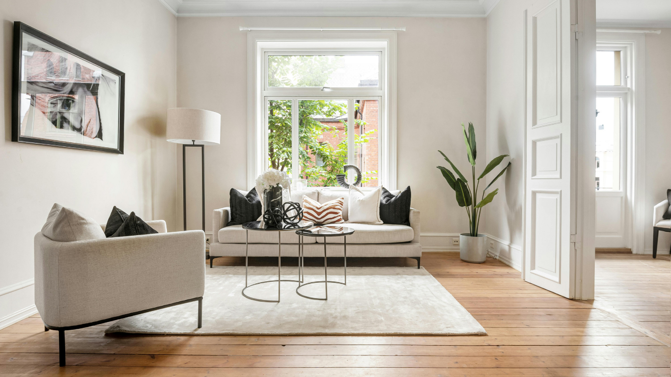 Bright living room with beige sofa, coffee table, rug, floor lamp, and large window view