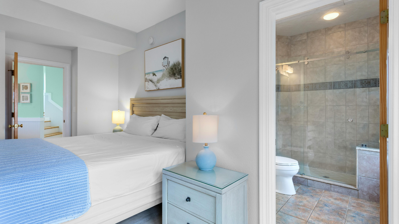 Bright bedroom with blue accents and an adjoining tiled bathroom visible through an open doorway