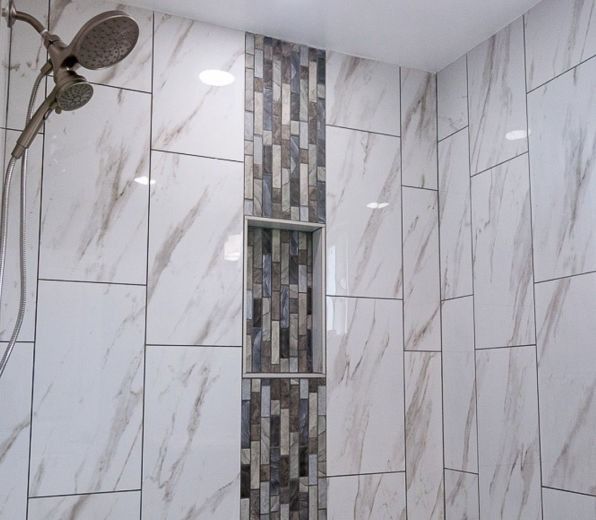 Modern tiled shower with a showerhead and vertical mosaic accent strip