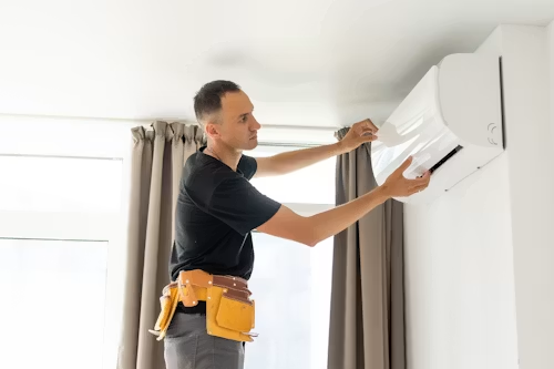 Technician installing a wall-mounted air conditioner in a bright room