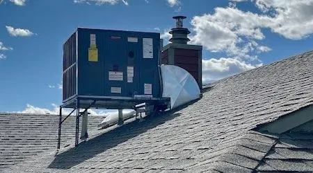 Blue rooftop HVAC unit on a shingled roof under a cloudy sky