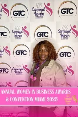 Woman at an awards ceremony, posing in front of a backdrop with logos and text 