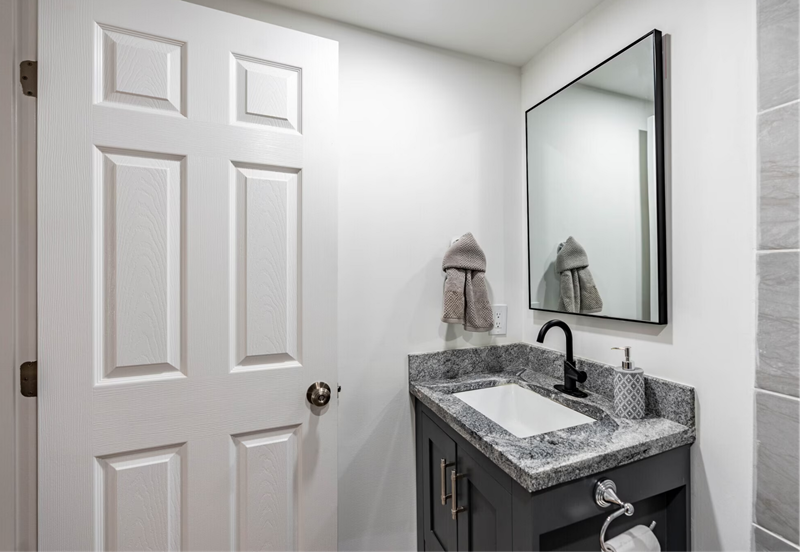 Nashville, TN Modern Apartments - Riverwalk 803 - Bathroom With Sink, Granite Countertops, Dark Cabinetry, And Mirror.