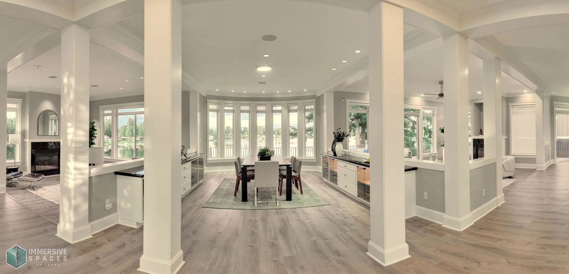 Spacious, bright dining room with large windows, a table, and chairs. White walls and columns.