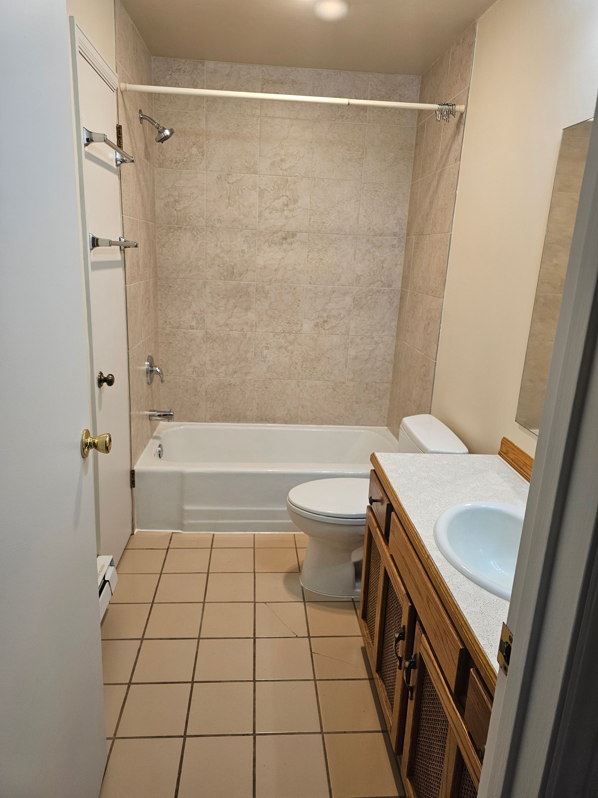 A bathroom with a tub , toilet , sink and shower.
