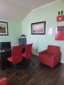 Home office with red chairs and armchair, computer desk, and mint green walls.