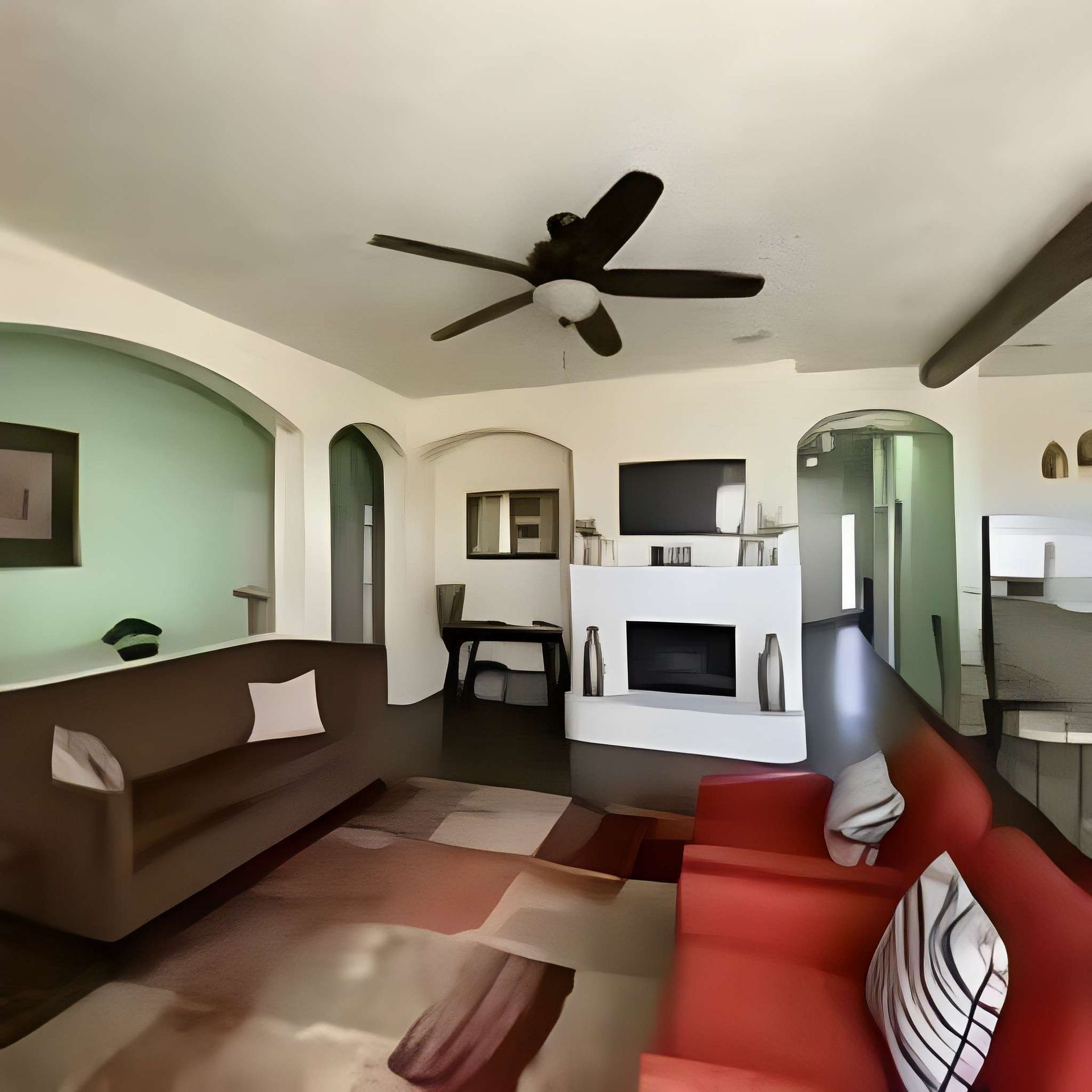 Living room with brown sofa, red chair, ceiling fan, fireplace, and arched doorways