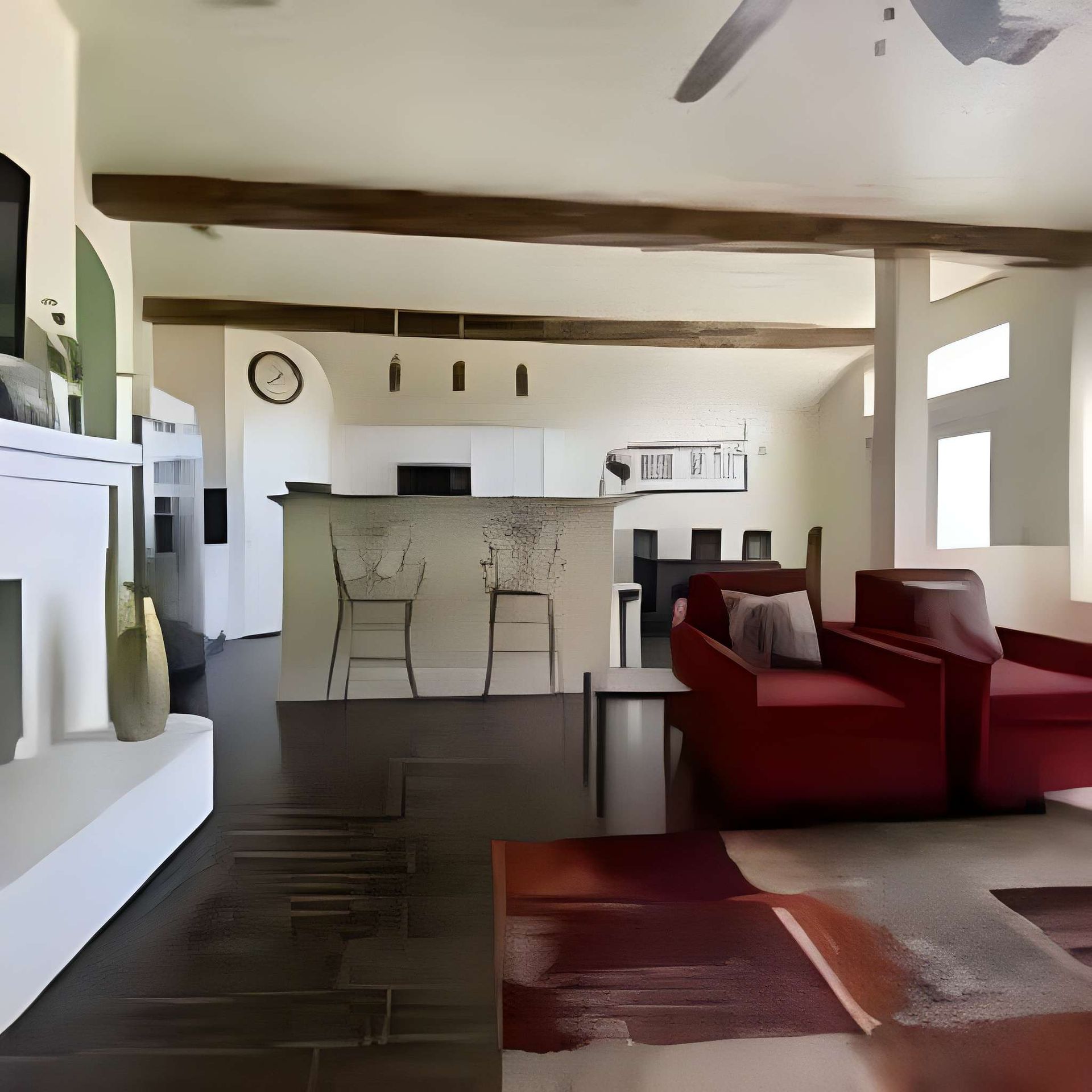 Living room with red sofas, patterned rug, and open kitchen with bar stools