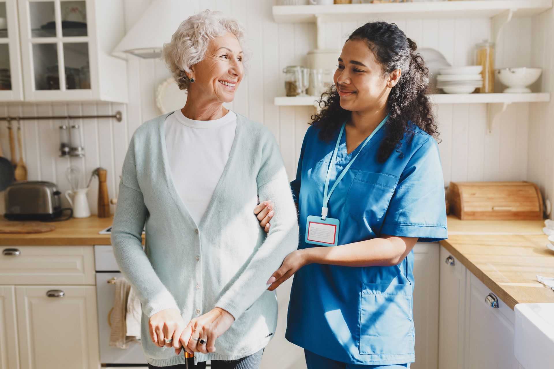 A person in blue scrubs with an American flag scarf holds hands with a person in a red shirt wearing a patriotic lei.