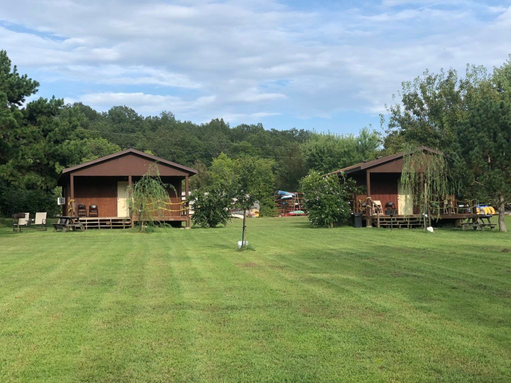 There are two cabins in the middle of a grassy field.