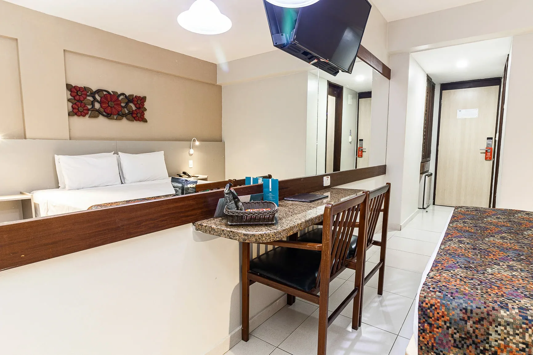 Quarto de hotel moderno com duas camas, uma pequena mesa de jantar e um tapete estampado para o banco.