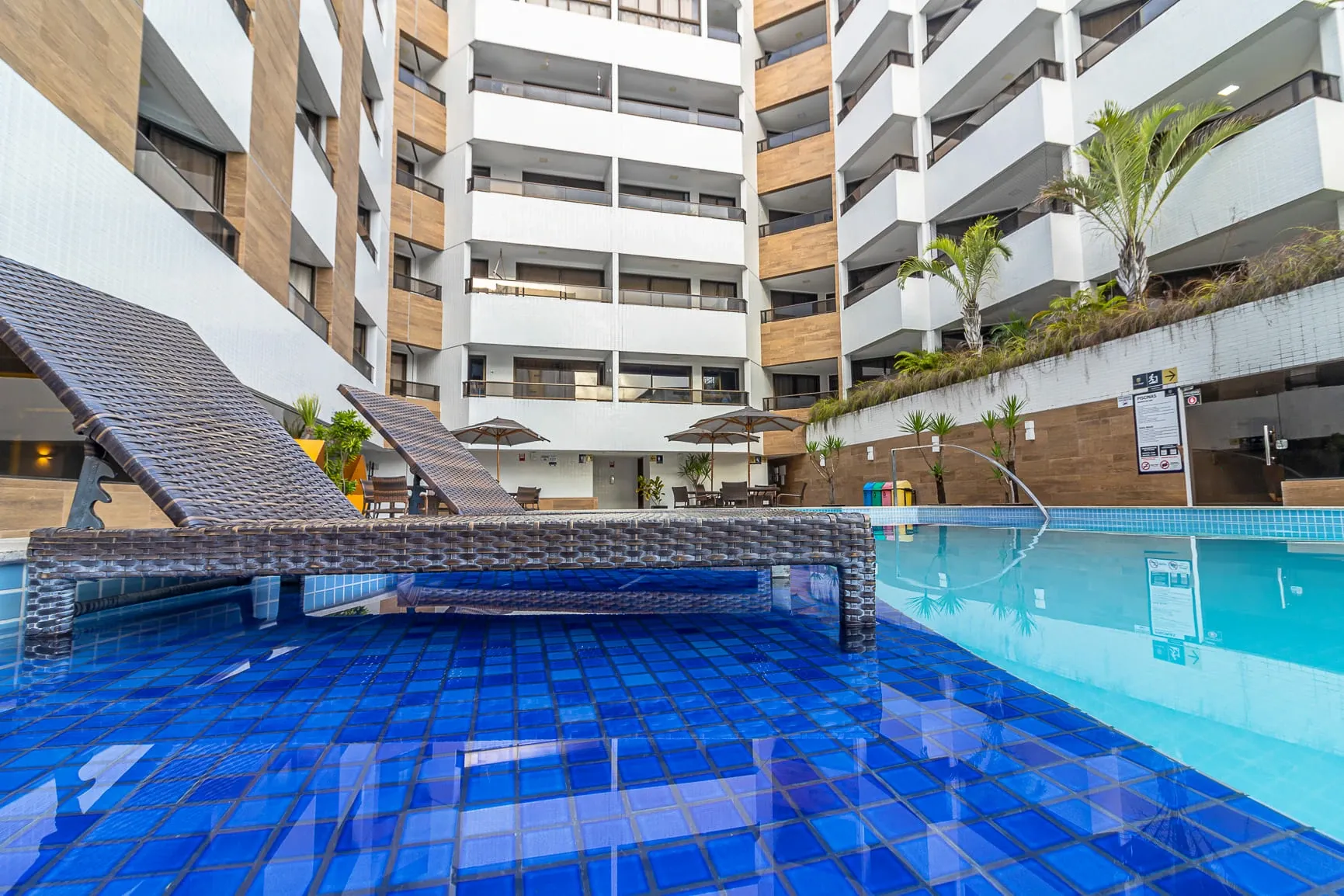 Pátio de apartamento moderno com piscina revestida de azulejos azuis e área de estar.