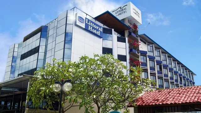 Prédio de escritórios moderno, envidraçado, com sinalização azul e telhado de telhas vermelhas na fachada.
