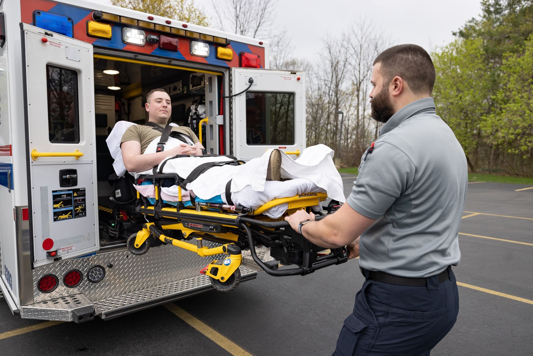 Paramedic wheeling a patient on a stretcher into an ambulance in a parking lot