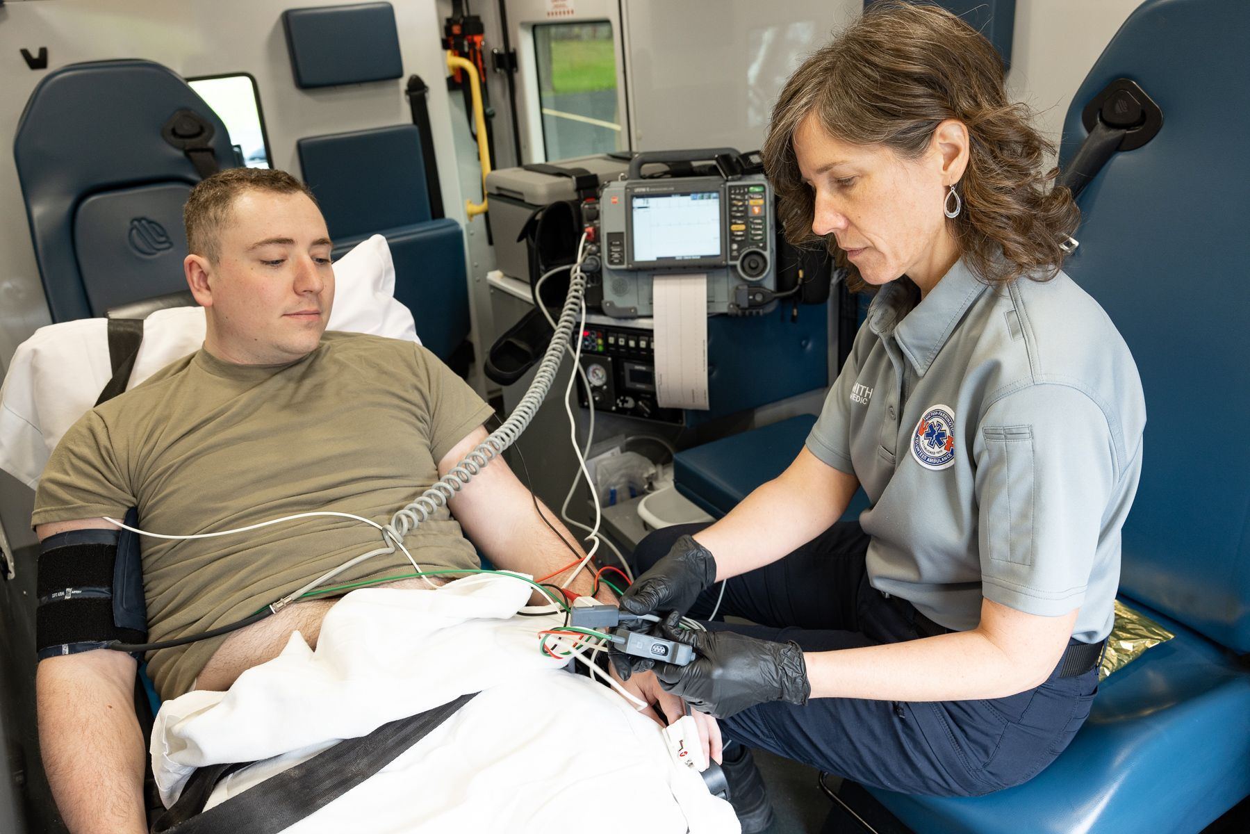 A Victor Farmington Ambulance paramedic monitors a patient's vital signs (training scenario)