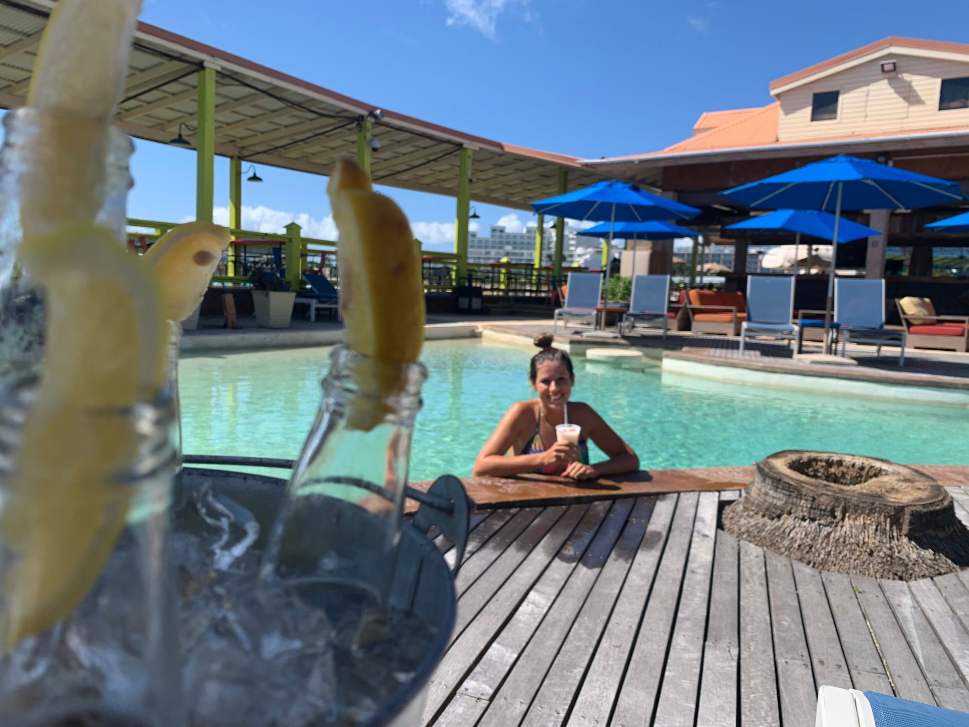Woman relaxing on a lounge chair by a private pool; white building with blue sky and palm trees.