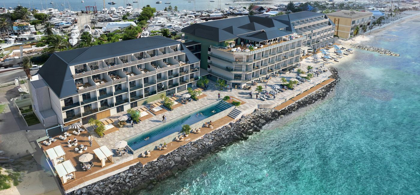 Aerial view of a modern beachfront hotel with a pool and ocean access.