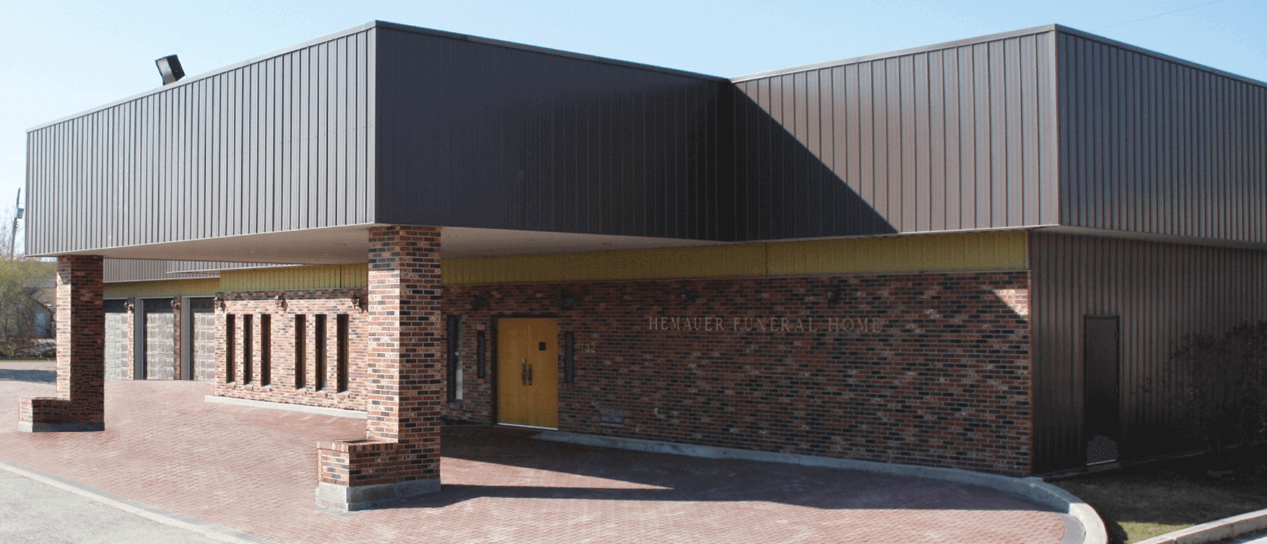Modern low-rise brick building with corrugated metal roof and covered entryway