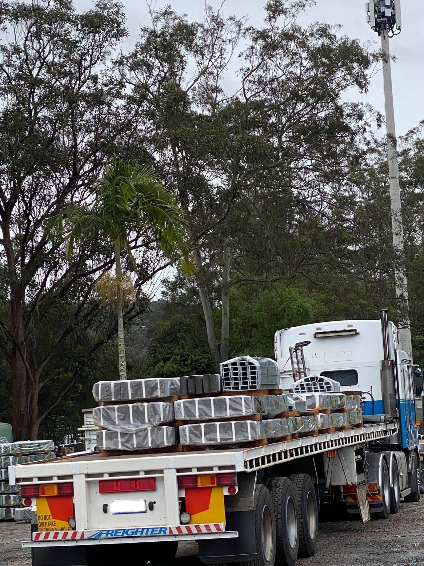 Truck With a Flatbed Trailer Loaded With Wrapped Metal Beams — Concrete Sleepers NSW - Port Macquarie in Central Coast, NSW