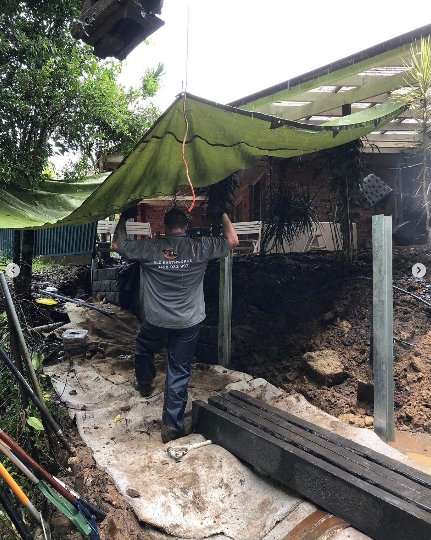 Man Carrying Object Under a Green Tarp, Construction Site — Concrete Sleepers NSW - Port Macquarie in Sancrox, NSW