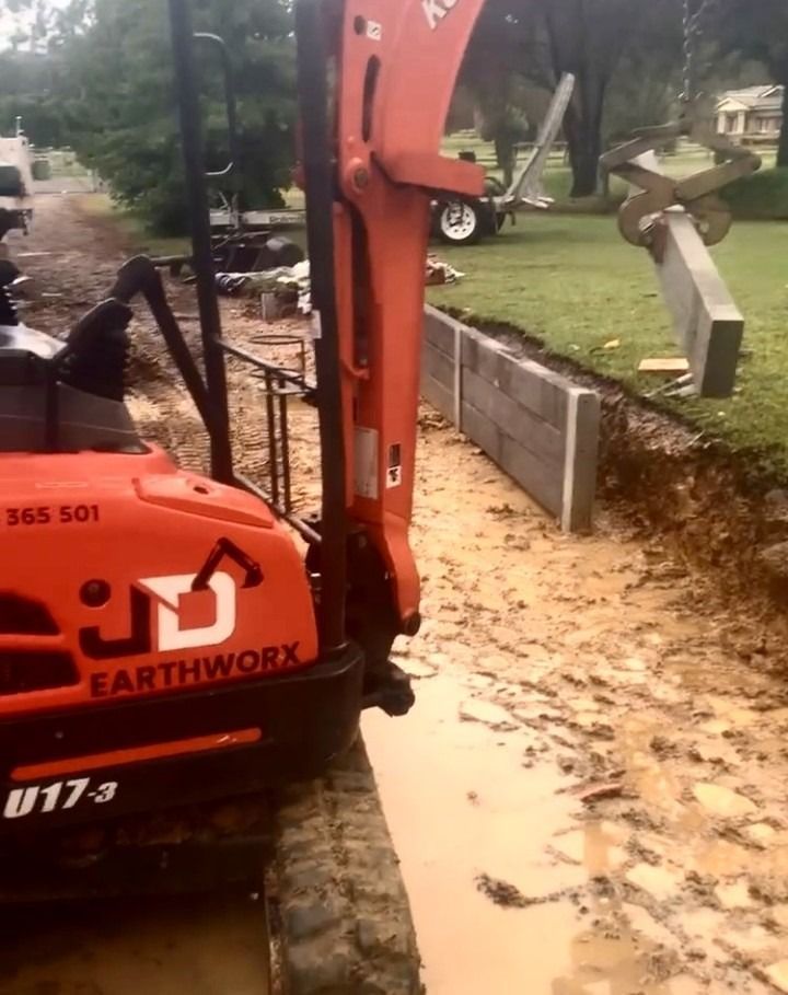 Orange Excavator Digging Near a Concrete Retaining Wall — Concrete Sleepers NSW - Port Macquarie in Sancrox, NSW