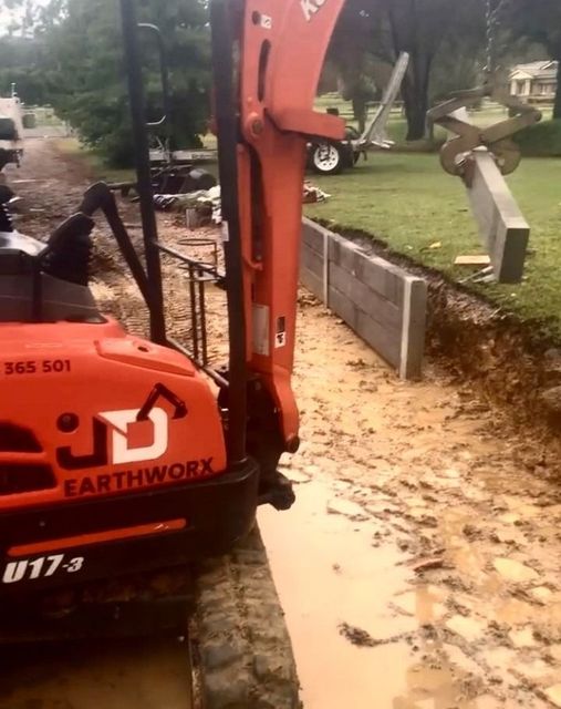Orange Excavator Digging Near a Concrete Retaining Wall — Concrete Sleepers NSW - Port Macquarie in Sancrox, NSW