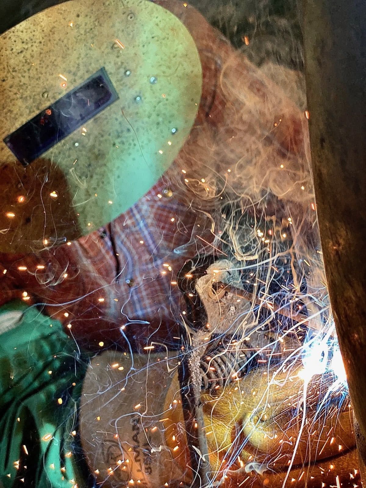 Close-up of a welder in a protective mask amid bright sparks and smoke