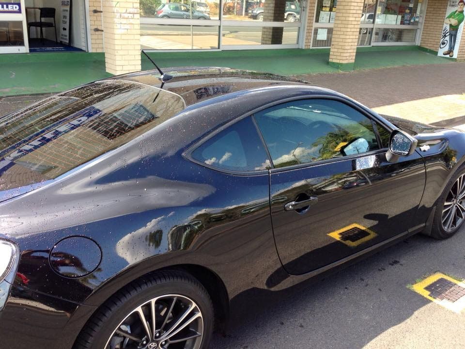 A Black Sports Car Is Parked In Front Of A Building — Staunch Window Tinting In South Lismore, NSW