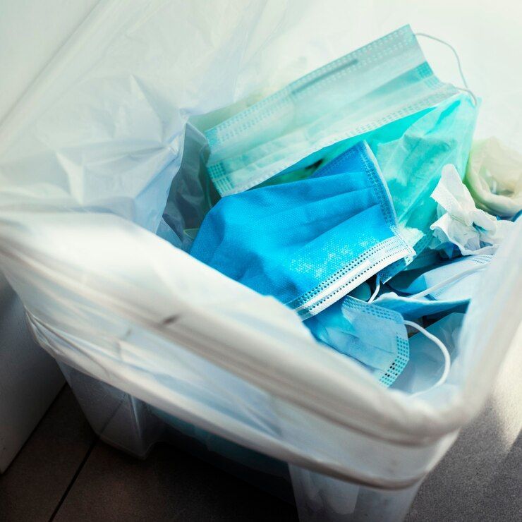 A trash can filled with surgical masks and gloves