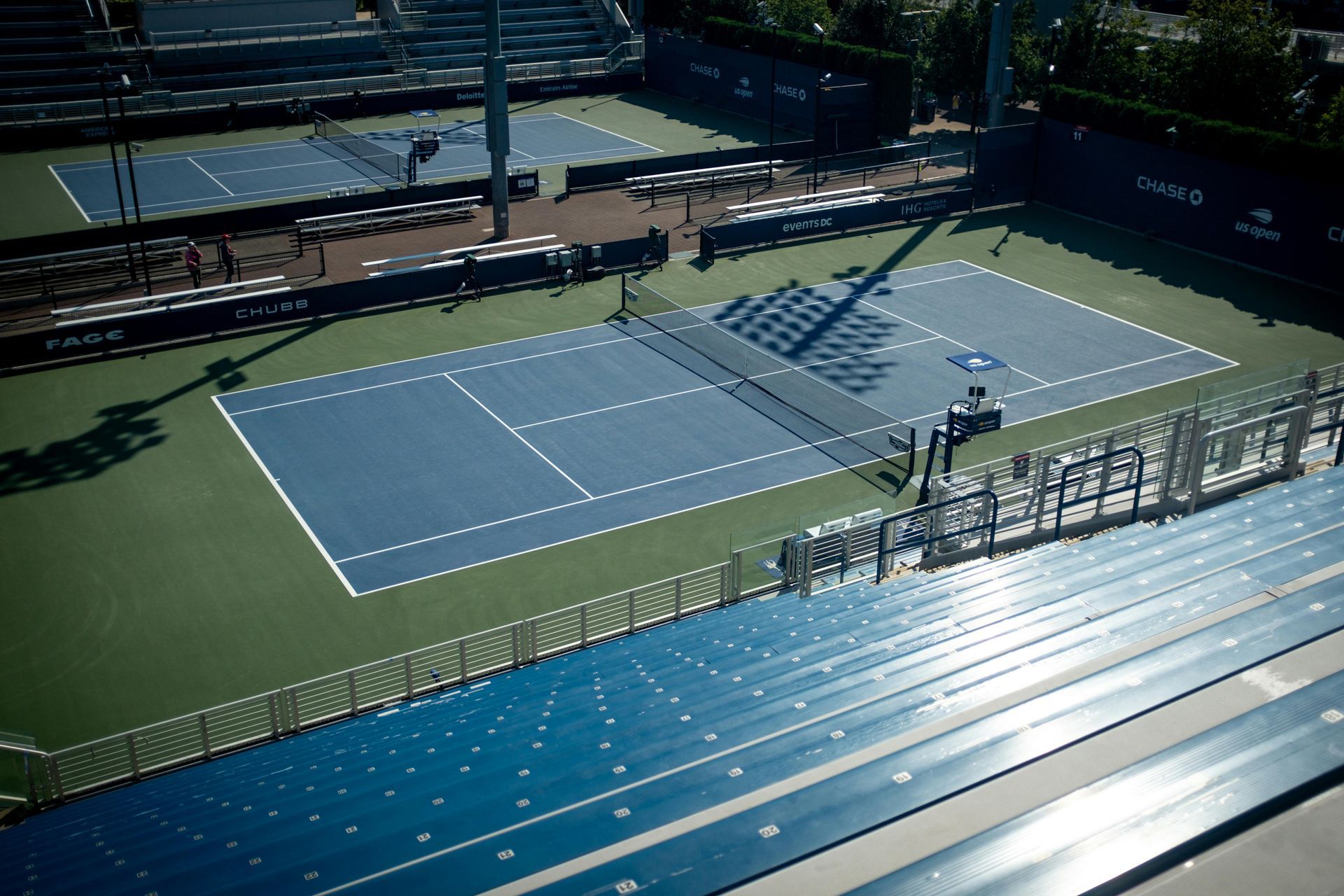 An aerial view of a tennis court with bleachers in the background