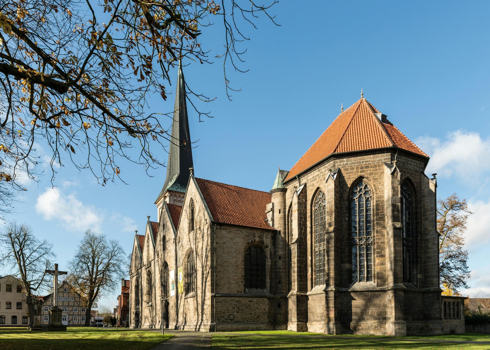 A church with a red tiled roof and a cross in front of it