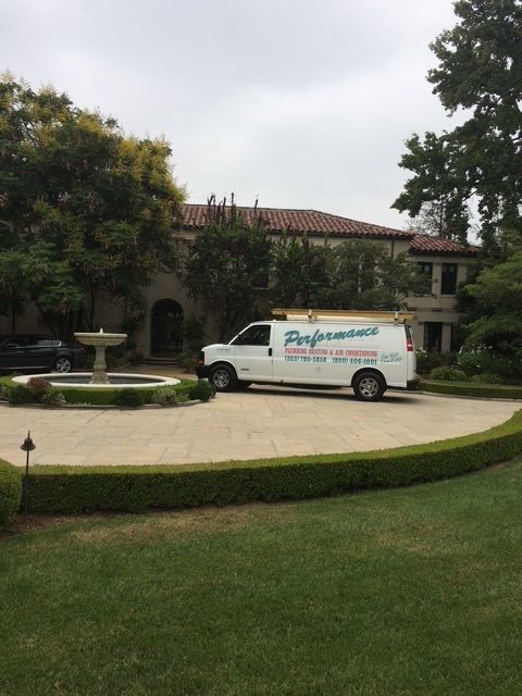 White delivery van parked in front of a large house with a fountain and landscaped lawn