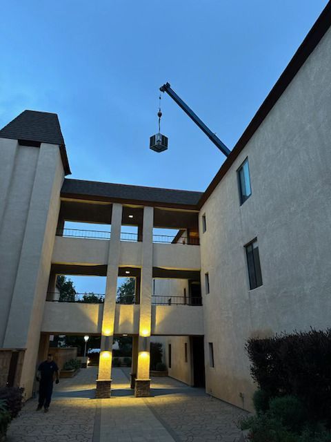 Modern apartment courtyard with a crane hoisting a load overhead at dusk