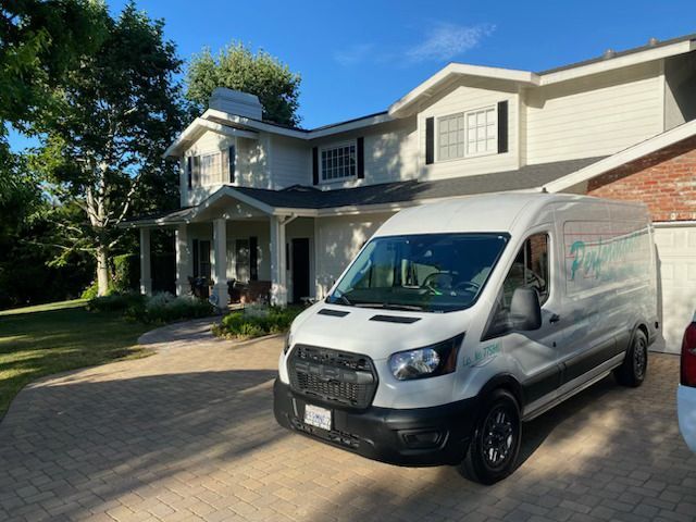 White delivery van parked in front of a two-story suburban house with a brick driveway.