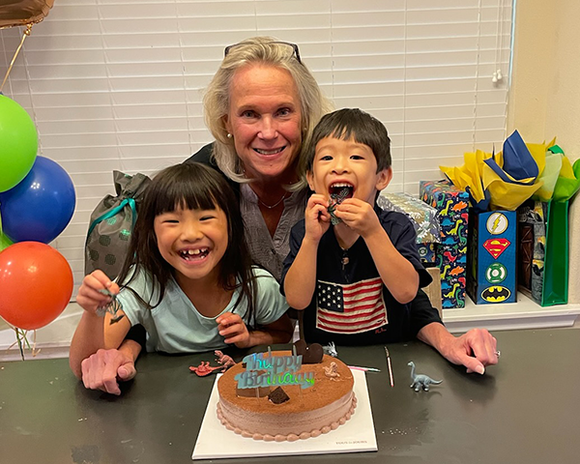 A woman and two children are sitting at a table with a birthday cake.