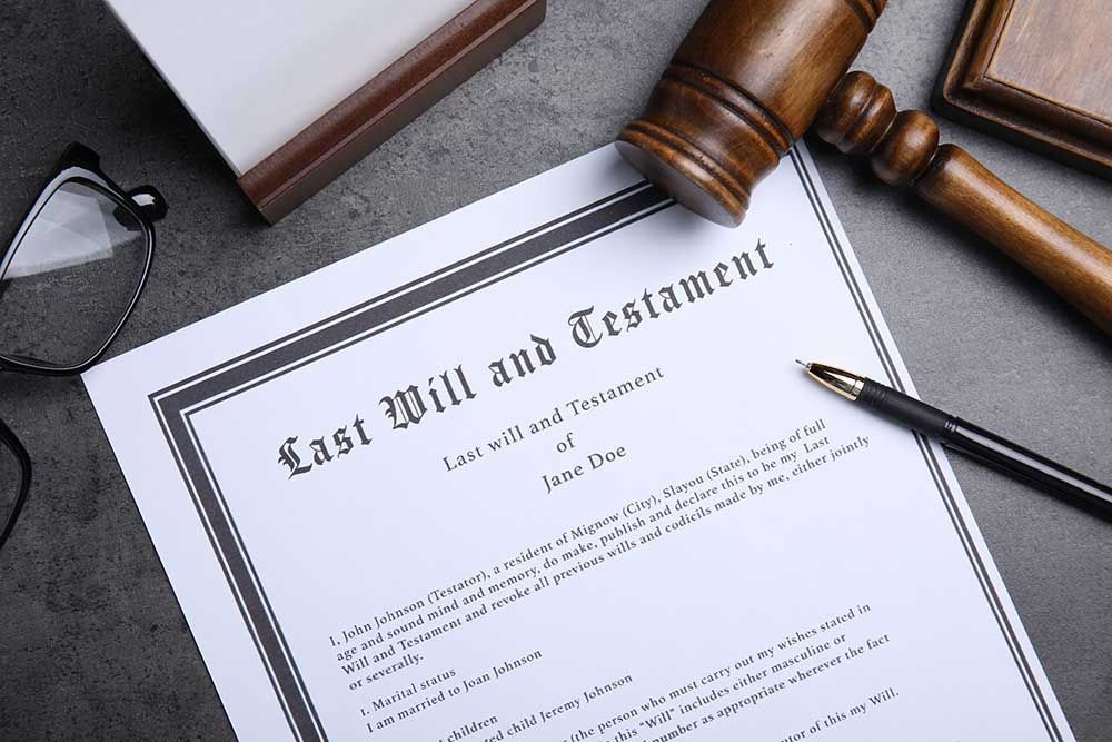 A last will and testament is sitting on a table next to a judge 's gavel and glasses.