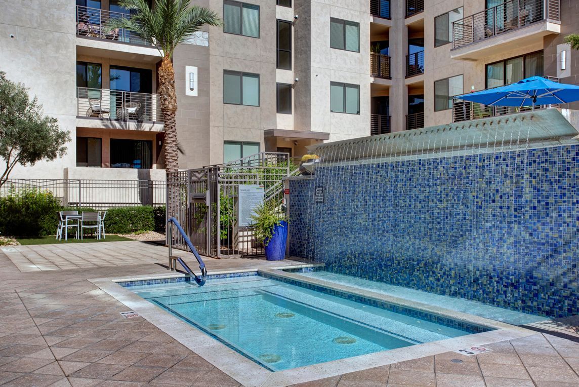 A large swimming pool with a waterfall in front of a building.