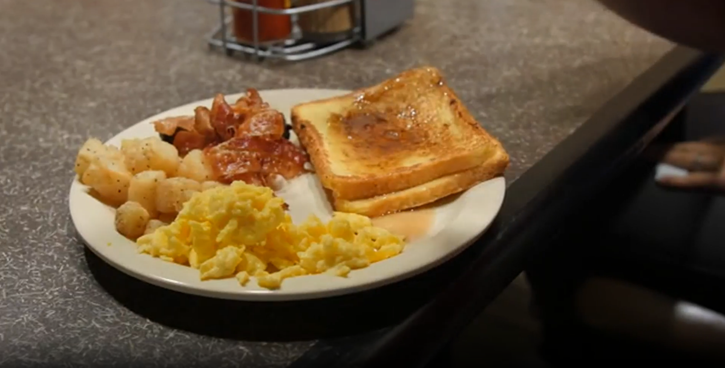 Breakfast plate with toast, scrambled eggs, potatoes, and bacon on a table