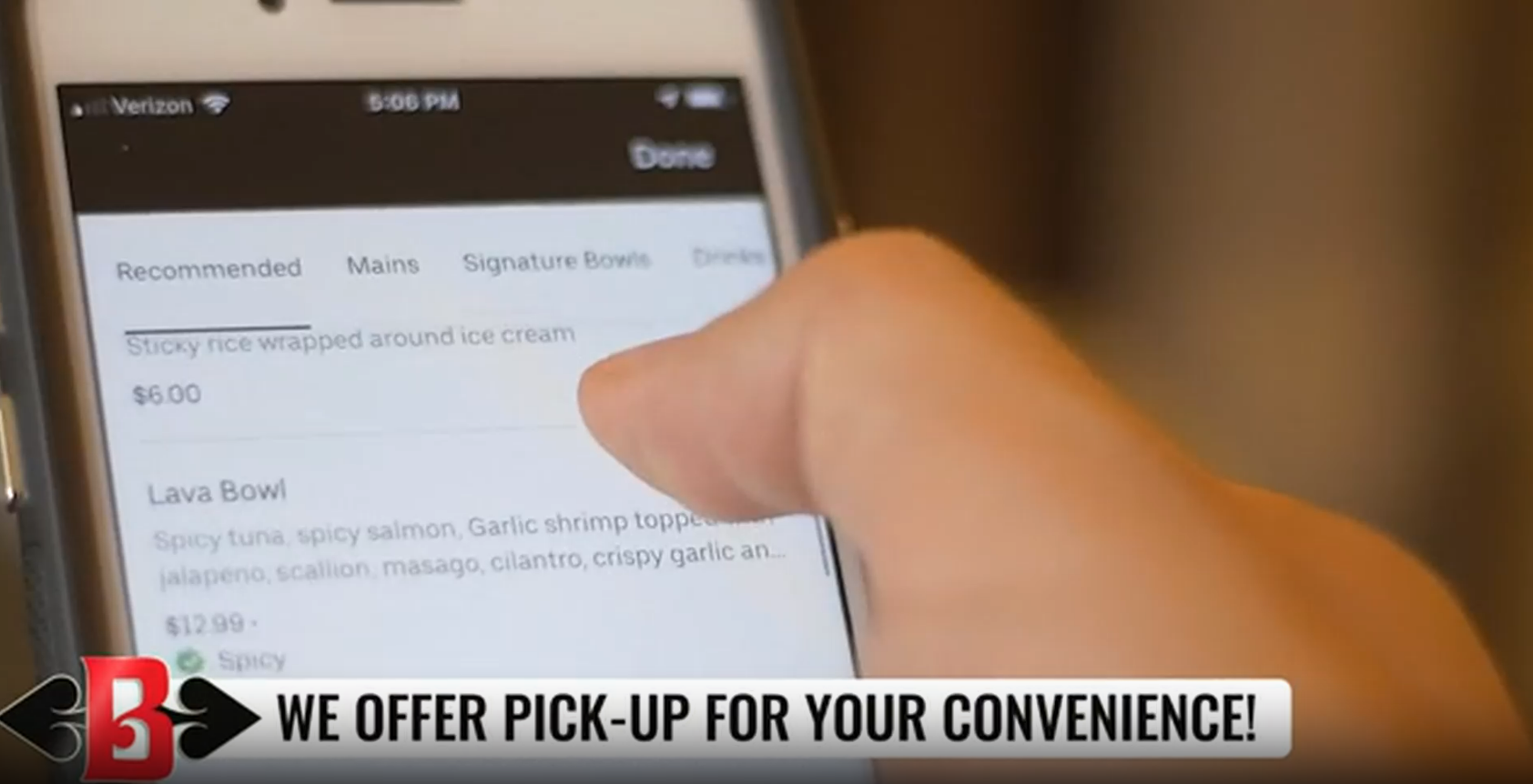 Hand using a smartphone with a delivery app open, and a banner reading “We offer pick-up for your convenience.”