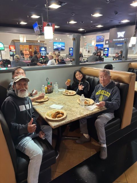 Three people at a diner booth with plates of food, smiling in a casual restaurant.