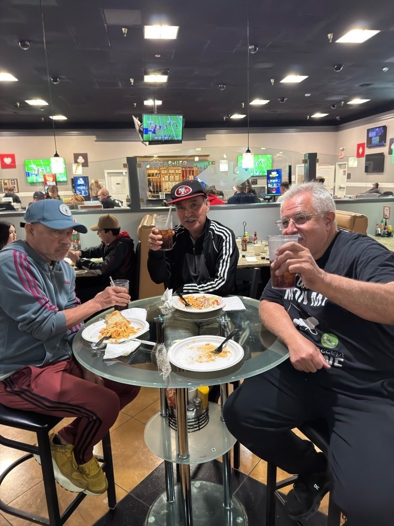Three people sit at a diner table, raising drinks and eating breakfast.