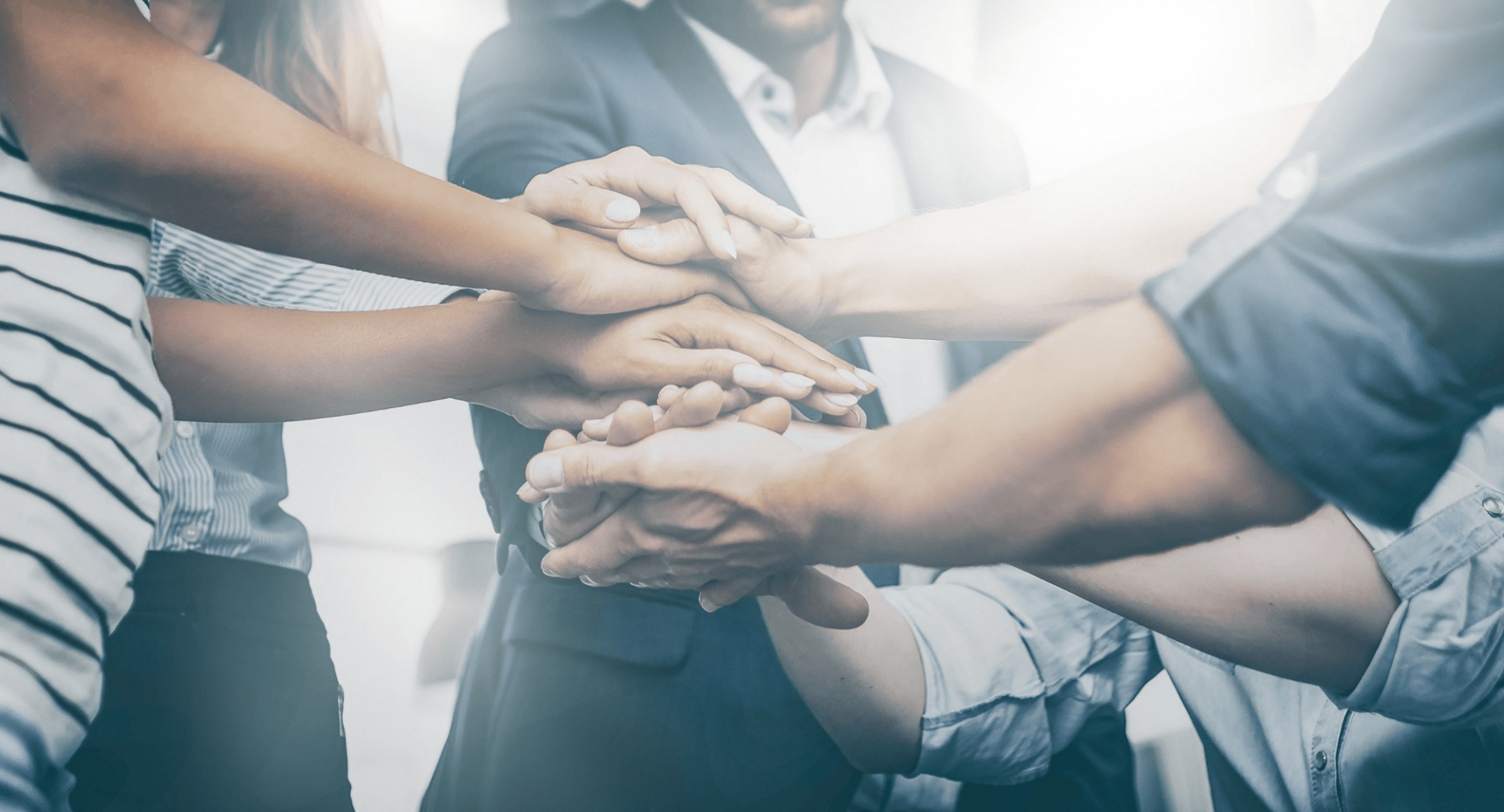 A group of people are putting their hands together in a huddle.