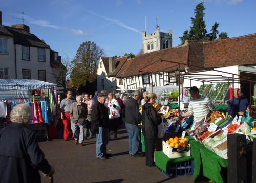 A group of people are shopping at a market with a church in the background