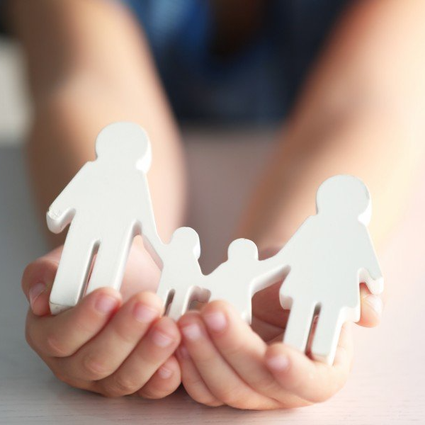 Child's hands holding a white wooden family figure.