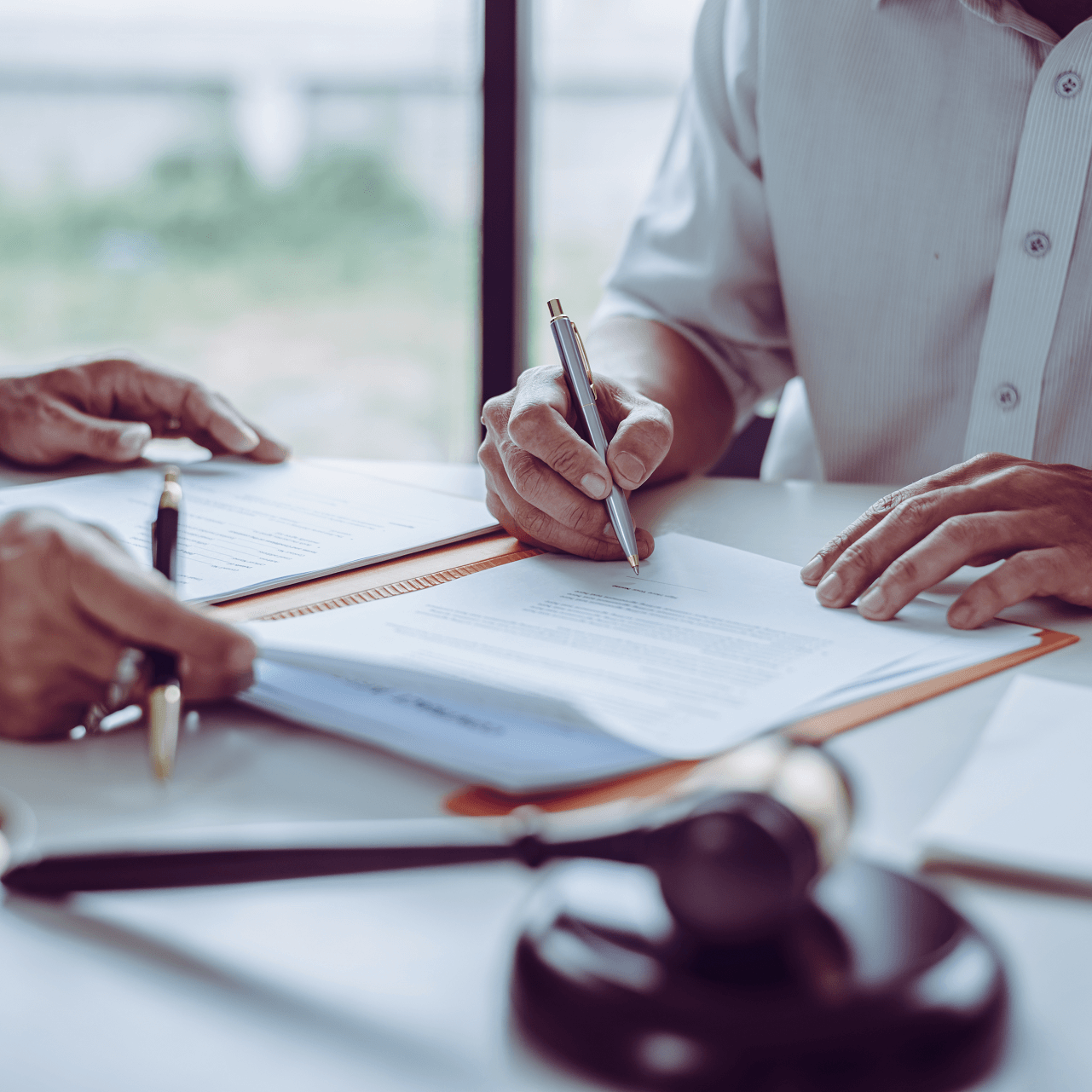 Two people signing documents at a table with a gavel.