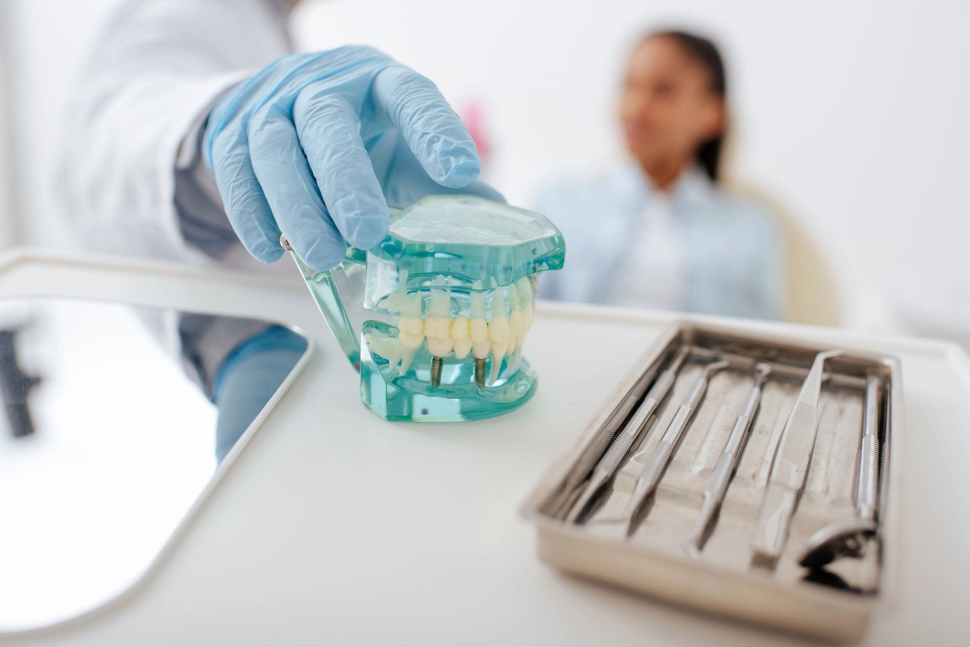 Un modello dentale che mostra una fila di denti protesici bianchi incastonati in una base di plastica blu traslucida.