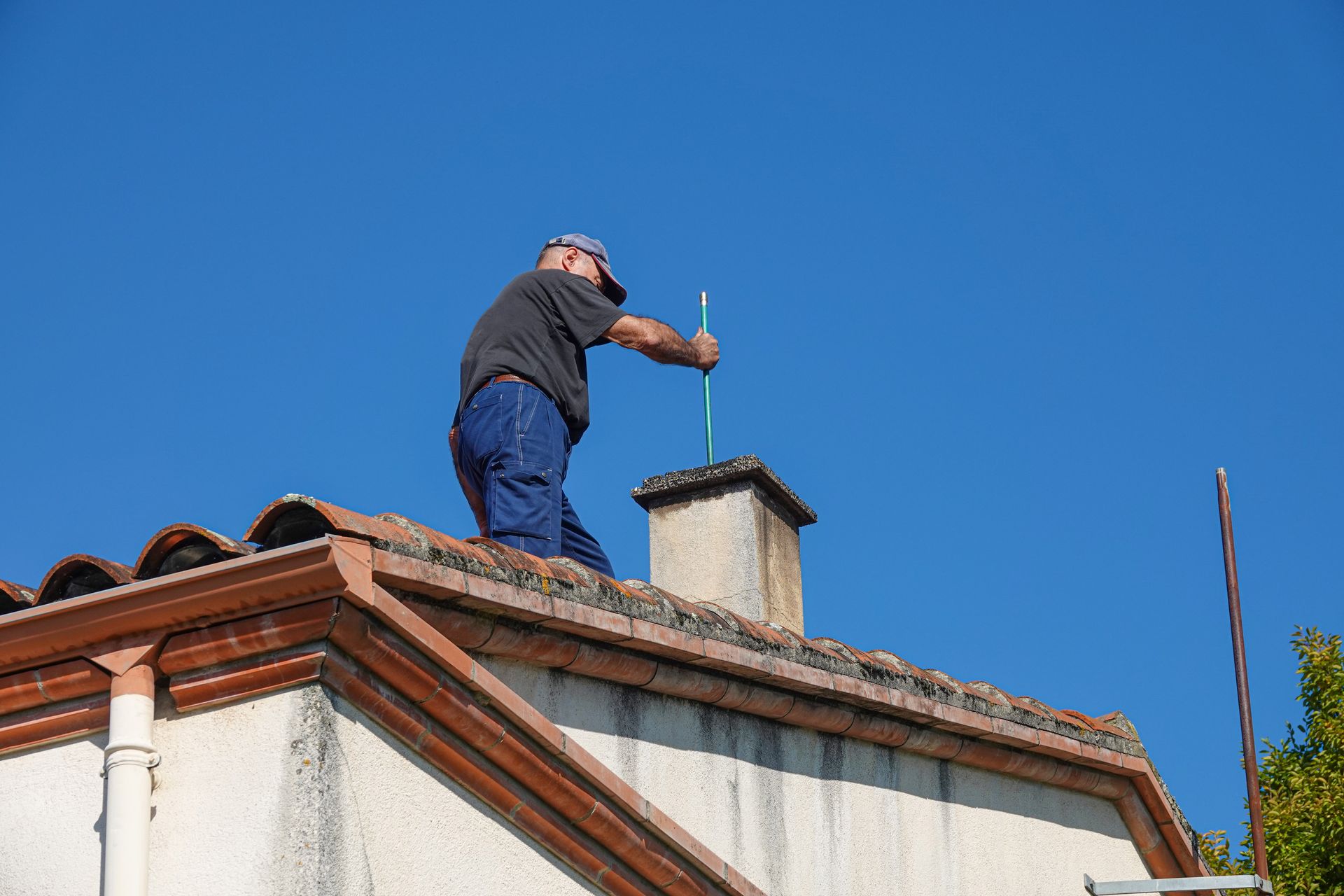 A person works on a chimney atop a house.